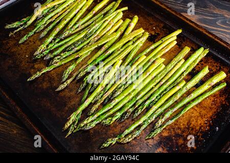 Geröstete Spargelspangen auf einer Pfanne: Gerösteter Spargel, gewürzt mit nativem Olivenöl extra, koscheres Salz und schwarzem Pfeffer Stockfoto