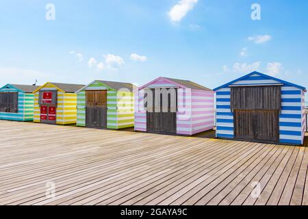 Strandhütten mit pastellfarbenen Bonbons am Pier in Hastings, East Sussex Stockfoto