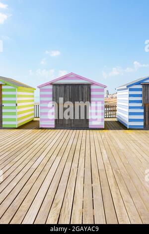 Strandhütten mit pastellfarbenen Bonbons am Pier in Hastings, East Sussex Stockfoto