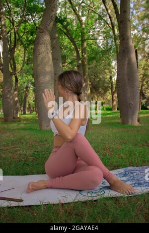 Vertikal Nahaufnahme einer nicht erkennbaren jungen Frau, die im Sommer an einem sonnigen Tag im Stadtpark Pilates posiert. Pilates Outdoor 2021. Stockfoto