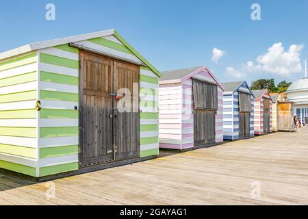 Strandhütten mit pastellfarbenen Bonbons am Pier in Hastings, East Sussex Stockfoto
