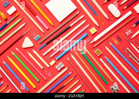 Schulbedarf auf rotem Papier Hintergrund - Ansicht von oben Stockfoto