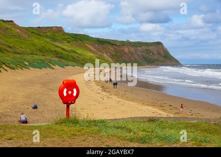 Die Menschen laufen am unberührten Strand von Cattersty Sands in Skinningrove Cleveland UK entlang und ein Mann läuft mit seinem Hund Stockfoto