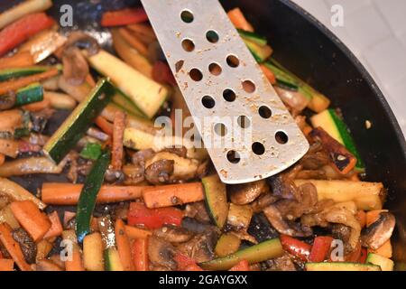 Foto von Lebensmitteln, die in der Küche gekocht werden, Gemüse in der Pfanne braten Stockfoto