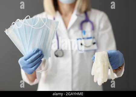 Der Arzt hält medizinische Schutzmasken und Handschuhe in den Händen Stockfoto