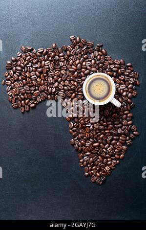 Geröstete Kaffeebohnen Formen Landkarte des Afrika auf Tafel mit einer Tasse Kaffee. Konzept der großen Kaffeeproduzenten weltweit. Stockfoto