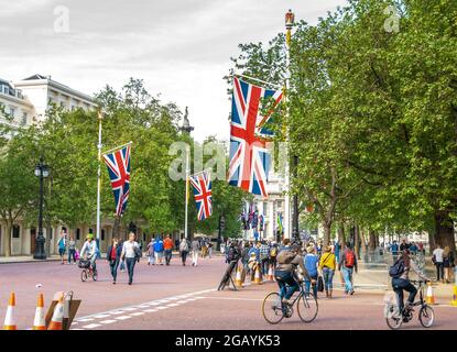 London - UK, 2015-05-10: Londen feiert den 70. Jahrestag des Endes des Zweiten Weltkriegs in Europa am VEday, dem Gedenken an den Tag des Sieges in Europa. Die Menschen schlendern und radeln die Mall entlang, eine von Bäumen gesäumte königliche Straße, die vom Trafalgar Square zum Buckingham Palace führt und auf beiden Seiten mit britischen Flaggen geschmückt ist. Hier mit Blick auf den Trafalgar Square. Im Hintergrund erhebt sich die Statue von Admiral Horatio Nelson auf der Nelson-Säule knapp über den Bäumen. Foto archivieren. Stockfoto