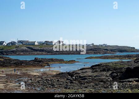 Trearddur Bay, Anglesey, Wales. Felsige Küste. Wunderschöne Küstenlandschaft. Niedrige Klippen und ein breiter Sandstrand bei Ebbe. Blauer Himmel und Kopierbereich Stockfoto