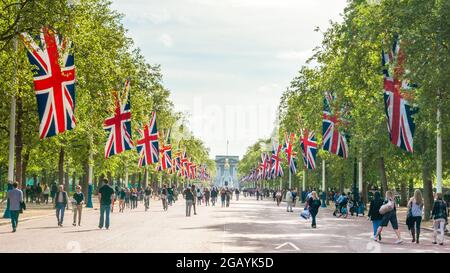 London - Vereinigtes Königreich, 2015-05-10. Londen feiert am VEday, dem Gedenken an den Tag des Sieges in Europa, den 70. Jahrestag des Endes des Zweiten Weltkriegs in Europa. Die Menschen schlendern die Mall entlang, eine von Bäumen gesäumte königliche Straße, die vom Trafalgar Square zum Buckingham Palace führt und auf beiden Seiten mit britischen Flaggen geschmückt ist. Hier mit Blick auf den Buckingham Palace. Foto archivieren. Stockfoto