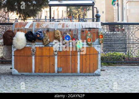 Souvenirladen in Icheri Sheher in Baku. Sowjetische und ukrainische Militärhüte mit Emblem verkauft draußen auf dem Bürgersteig. Stockfoto