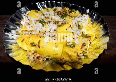 Khandvi ein traditionelles und authentisches Gujarati-Gericht, das als herzhafte Snacks serviert wird. Temperiert und garniert mit geriebener Kokosnuss, grünem Chilly und Sesam Stockfoto