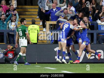 Harry Newman von Leeds Rhinos (Mitte rechts) feiert den vierten Spielversuch seiner Mannschaft mit Teamkollegen und Fans, während Jake Mamo von Warrington Wolves (links) während des Betfred Super League-Spiels im Emerald Headingley Stadium, Leeds, niedergeschlagen aussieht. Bilddatum: Sonntag, 1. August 2021. Stockfoto