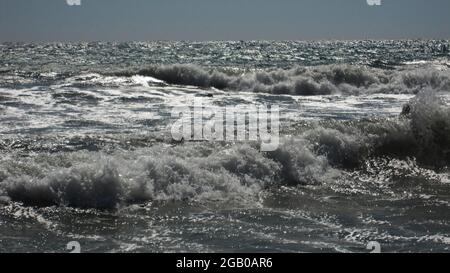 Wunderschöne blaue Meereswellen mit weißem Schaum aus nächster Nähe. Geschäftiges, heftiges Meer und Horizont im Hintergrund mit bewölktem, stürmischem Himmel. Minimalistisches Bild von Stockfoto