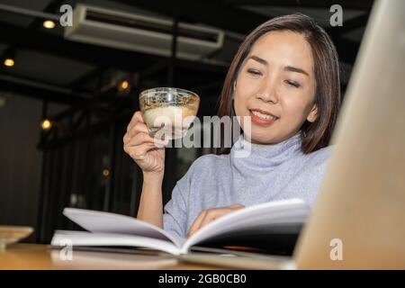 Asiatische Frau professionelle Designerin denkt über die Idee Konzept der Arbeit Projekte mit glücklichen Lächeln, während eine Tasse Kaffee in der smart o Stockfoto