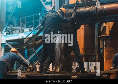 Arbeiter im Prozess der Arbeit mit großer Gussform Eisen auf Stahlwerk. Gießerei Werkstatt Innenraum. Typische metallurgische Anlage. Stockfoto