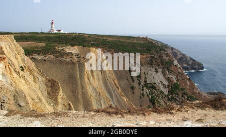 Weißer Leuchtturm auf der grünen Landzunge mit Blick auf den Atlantik, bei Cabo Espichel, Portugal Stockfoto