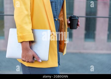 Unkenntliche Geschäftsfrau mit Computer, die in der Stadt herumläuft Stockfoto