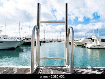 Leiter in das Wasser des kleinen Hafens der Marina von San Vincenzo, Provinz Livorno, Toskana, Italien, mit festfahrenden Booten und Yachten. Stockfoto