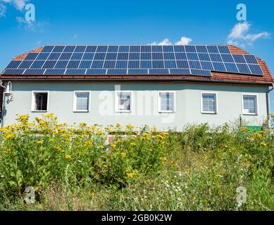 Solarzellen, die auf dem roten Ziegeldach eines Hauses Europa installiert sind. Modernes Dach vor dem Hintergrund eines blauen Himmels. Stockfoto