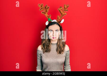 Junge hispanische Mädchen trägt Hirsch weihnachtshut mit ernsten Ausdruck im Gesicht. Einfach und natürlich Blick auf die Kamera. Stockfoto