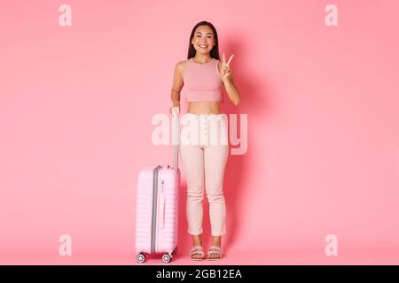 Reise-, Urlaub- und Urlaubskonzept. Cute asiatische Mädchen bereit, neue Länder zu erkunden, zeigt Frieden kawaii Zeichen und lächelnd als Reise ins Ausland Stockfoto