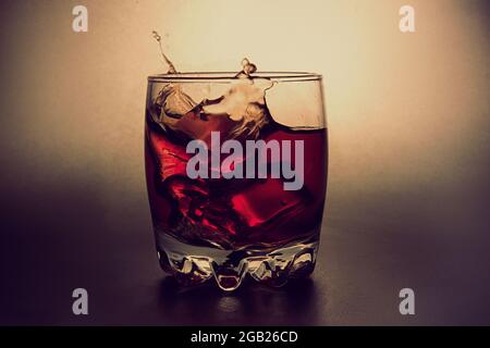Glas Whiskey mit Eiswürfeln und Spritzern von fallendem Eis. Stockfoto