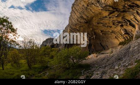 Blick auf Veli Badin, natürliche Steinklippe in den Felsen geschnitzt überlappen den Boden, an einem sonnigen Nachmittag. Majestätische Felsstruktur im slowenischen Kars Stockfoto