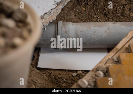 Kanalisationsrohr im Boden mit Papier ableiten, um herauszufinden, wo sich das Leck befindet. Kunststoffrohr wird aufgrund einer Leckage in der Dichtung der Verbindung repariert. Stockfoto