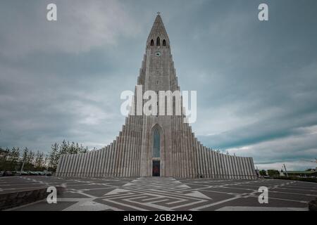 Hallgrimskirkja, eine luteranische Kirche mitten in Reykjavik, der Hauptstadt Islands, von vorne gesehen an einem bewölkten Sommertag. Stockfoto