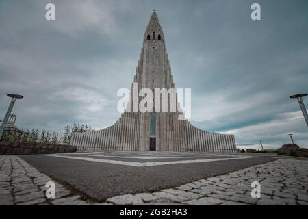 Hallgrimskirkja, eine luteranische Kirche mitten in Reykjavik, der Hauptstadt Islands, von vorne gesehen an einem bewölkten Sommertag. Stockfoto