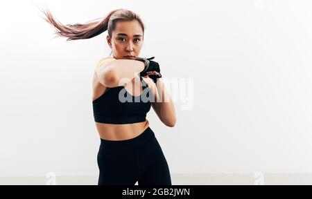 Frau beim Schattenboxen. Weibliche Sportlerin trägt Handschuhe. Stockfoto