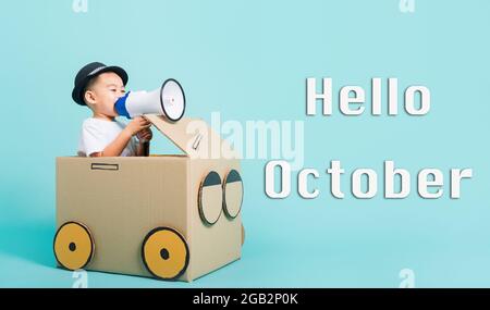 Hallo Oktober, glücklich asiatische Kinder Junge lächeln in fahren Spiel Auto kreativ von einem Karton Phantasie mit Megaphon, Studio auf blauem Hintergrund gedreht Stockfoto