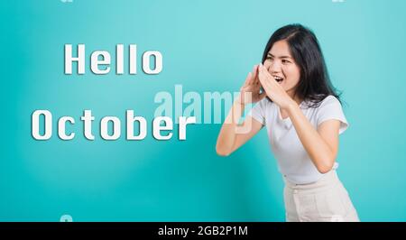 Hallo Oktober, Portrait Asian schöne glückliche junge Frau lächeln weiße Zähne tragen weißes T-Shirt stehen schreiend mit Händen decken Mund, Studio Schuss ich Stockfoto