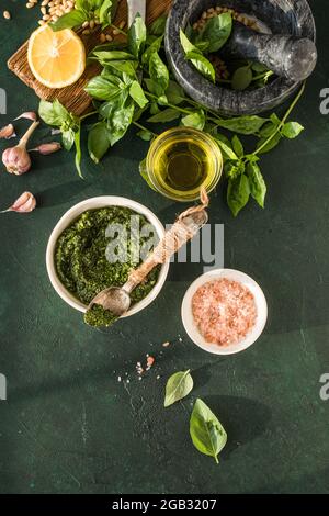 Pesto-Sauce in Schüssel mit Zutaten auf rustikalem grünen Tisch. Traditionelles italienisches Pesto-Rezept für Fettuccine, Pasta, Bruschetta. Stockfoto