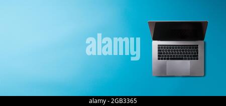 Flacher Schreibtisch mit Blick von oben und Laptop auf blauem Hintergrund. Speicherplatz kopieren. Stockfoto