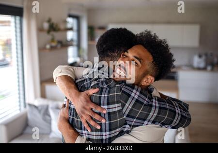 Junge glückliche Erwachsene Brüder in der Küche drinnen zu Hause, umarmt. Stockfoto