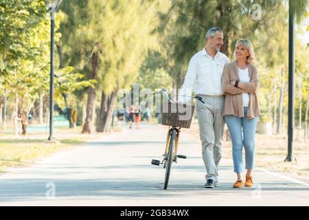 Alte Liebe Paar Wandern mit dem Fahrrad und reden im Park, Senior Romantiker Konzept Stockfoto