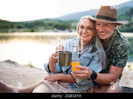 Glückliches Seniorenpaar auf Wandertour im Sommerurlaub, entspannen am See. Stockfoto