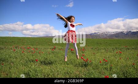 Happy girl Springen auf Tulpenfeld gegen Sky Stockfoto