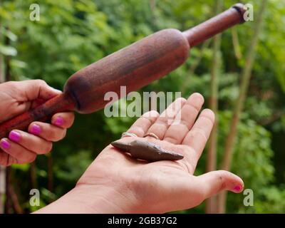 Hölzerne Chapati-Rolle mit Boden gemacht Spielzeug auf der Hand mit Vergleich über grüne natürliche Umwelt vorgestellt. Stockfoto