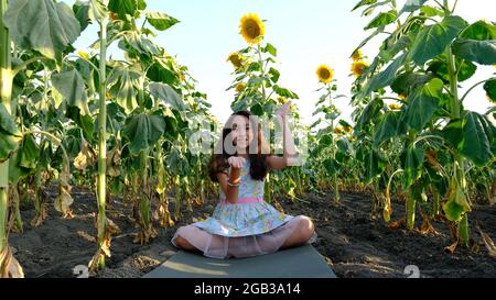 Ein schönes Mädchen praktiziert Meditation in einem Feld von Sonnenblumen. Stockfoto