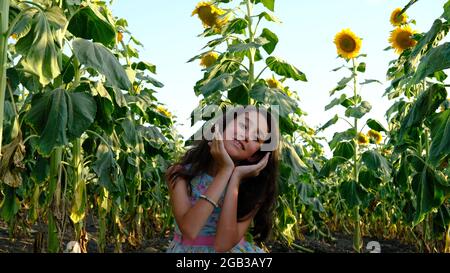 Ein schönes Mädchen praktiziert Meditation in einem Feld von Sonnenblumen. Stockfoto