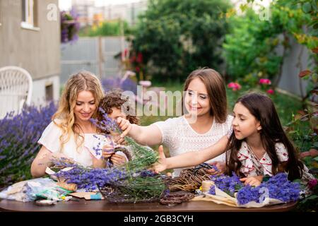 Frauen mit Töchtern, die Lavendelsträuße im Freien machen Stockfoto