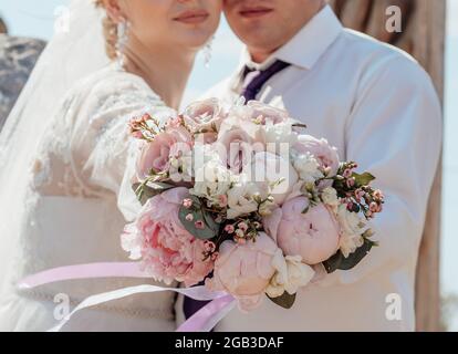 Bild von Mann und Frau mit Brautstrauß .Junges Ehepaar hält Hände, Zeremonie Hochzeitstag. Die Zahlen des frisch verpagten Paares Stockfoto