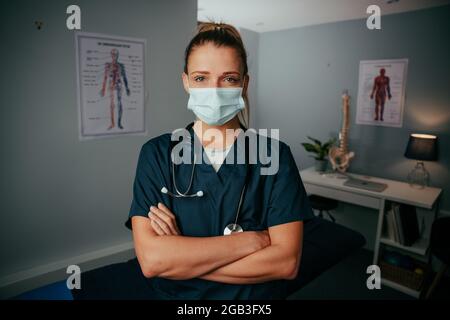 Kaukasische Krankenschwester, die in der Arztpraxis steht und eine chirurgische Maske trägt Stockfoto