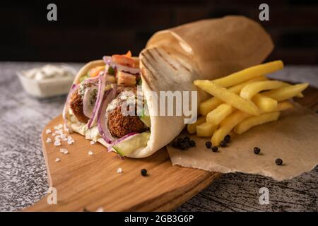 Döner Kebab, ein Shawarma in einer Grube aus frischem Gemüse und Fleisch. Mit großen Gewürzen. Restaurant serviert. Auf dunklem Hintergrund. Für Menüs und Werbung Stockfoto