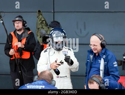 Damon Hill, kurz nachdem er beim Silverstone Classic 2021 aus dem Cockpit seines WM-siegreichen Formel-1-Autos FW18, umgeben von Mitgliedern des Williams Racing Heritage Teams, ausgefahren war Stockfoto