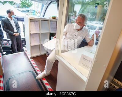 Mainz, Deutschland. August 2021. Dr. Eckhard Rix (r) hält in einem Impfbus eine Konsultation mit einer geimpfungswilligen Person ab (l, nicht im Bild); im Hintergrund steht Rheinland-pfälzischer Gesundheitsminister Clemens hoch (SPD, l). Nach den Angeboten in den Impfzentren des Landes und bei etablierten Ärzten sind nun sechs Impfbusse in allen Teilen von Rheinland-Pfalz unterwegs und ermöglichen Corona-Impfungen ohne Registrierung. Insgesamt werden sie bis Ende August an mehr als 200 Stationen anhalten. Kredit: Frank Rumpenhorst/dpa/Alamy Live Nachrichten Stockfoto