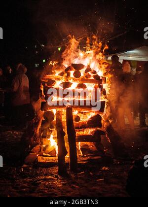 Brennendes Brennholz, Feuer aus der Nähe. Brennendes Lagerfeuer im Freien. Feuer mit Mauerwerk auf einem Picknick. Birkenbrennholz. Flammenzungen. Stockfoto