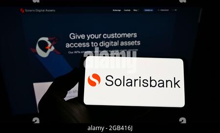 Person mit monbilem Telefon und Logo des deutschen Finanzdienstleisters solarisBank AG auf dem Bildschirm vor der Webseite. Konzentrieren Sie sich auf die Telefonanzeige. Stockfoto